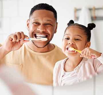 Dad and daughter brushing teeth in bathroom