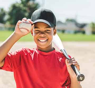 Smiling child holding bat and baseball