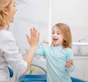 Smiling child giving dentist high-five