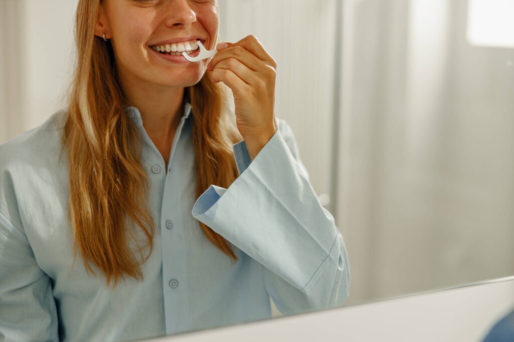 Woman smiling while flossing teeth